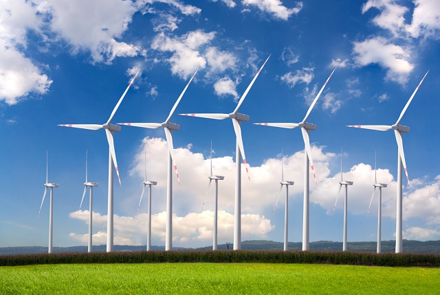 A large group of wind turbines making up a wind farm on land.