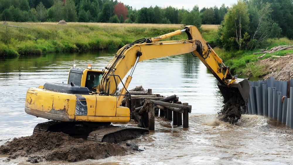 Excavator working in the small forest river, excavator bucket. Construction of the new bridge, bridge construction engineering