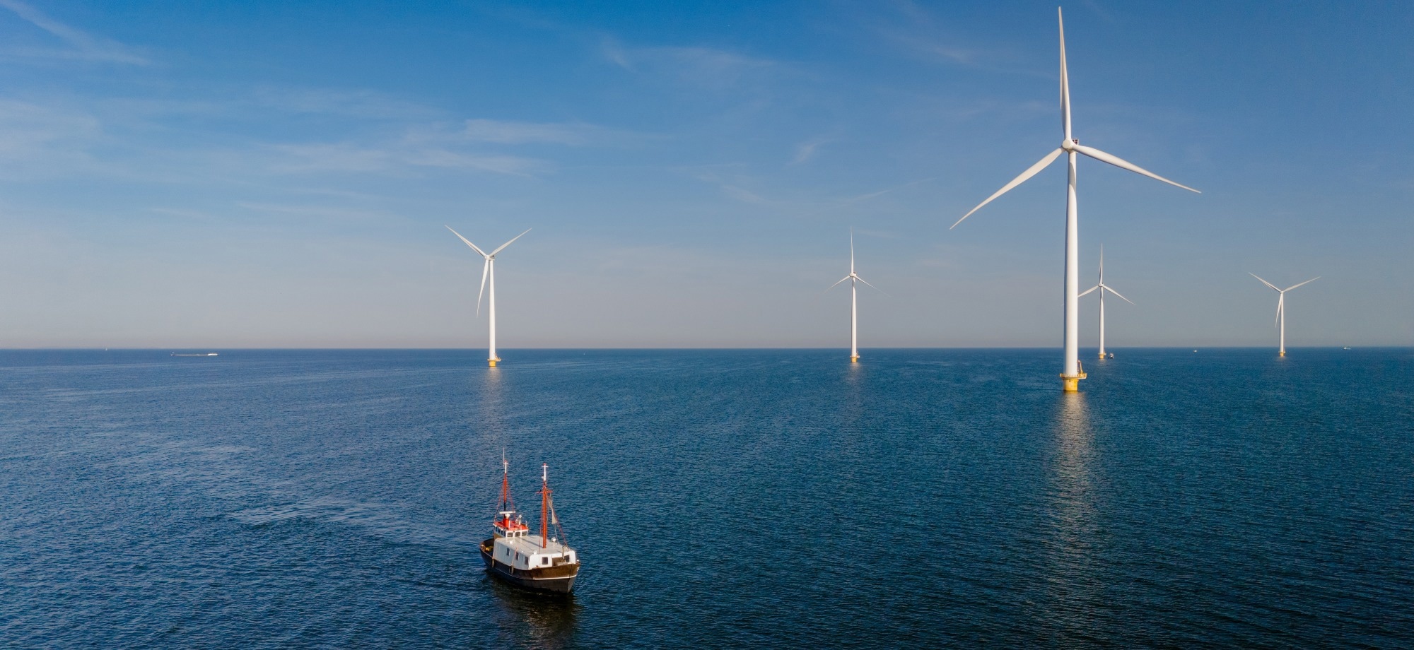 sea with boat and wind turbines in the background