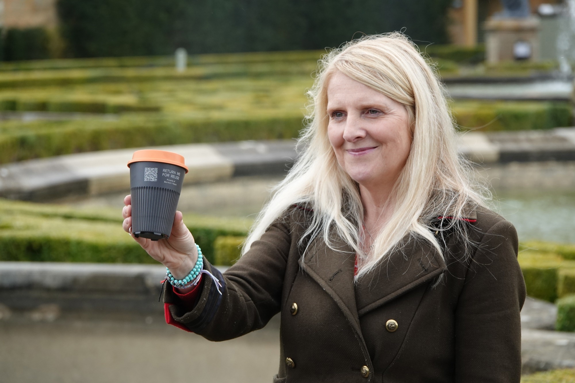 woman holds reusable coffee cup in hand