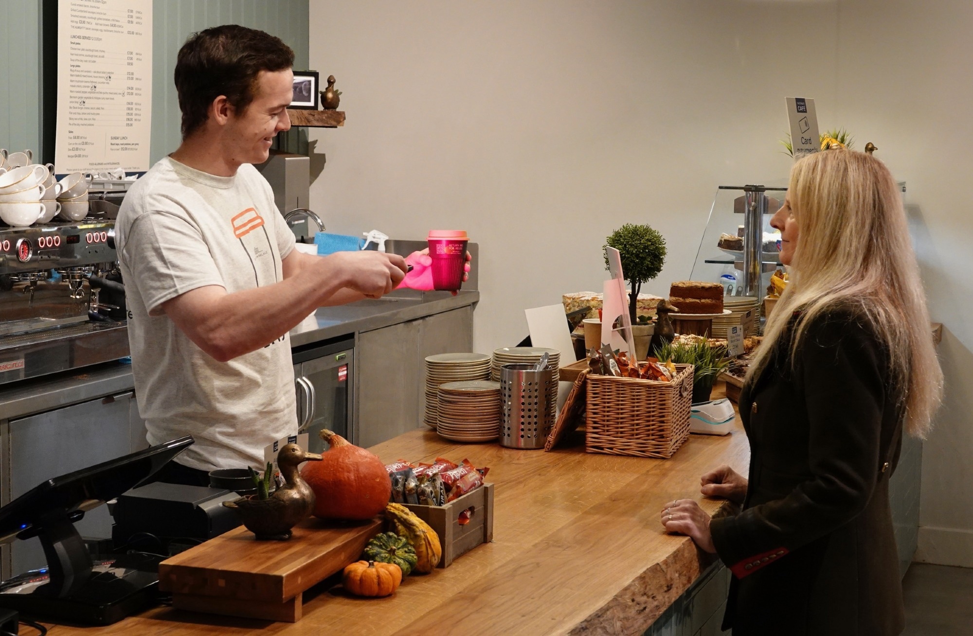 shop worker scans coffee cup for reuse