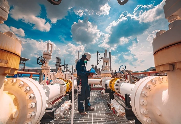 Worker wearing personal protective equipment on a large boat with a blue sky in the background.
