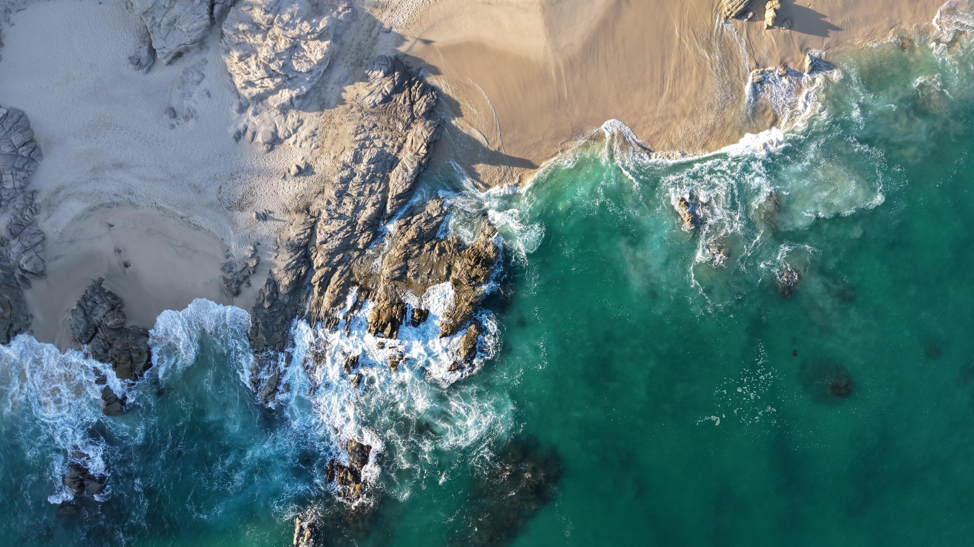 ocean water and sand and rocks from above