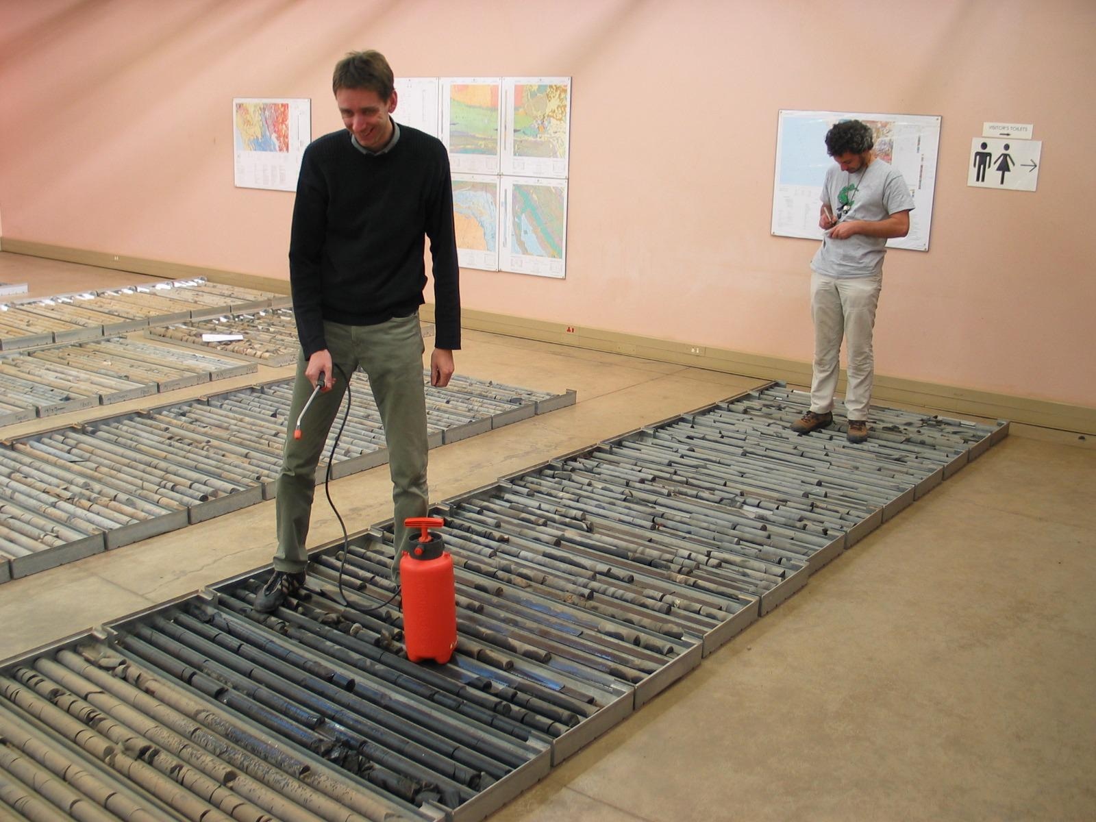 Biogeochemist Simon Poulton, left, sprays water on drill core to see sedimentary rocks and select samples for research.