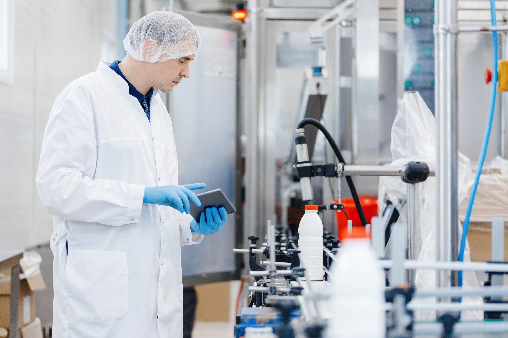 Engineer operator inspecting milk bottles production line dairy factory industry, automatic conveyor for transporting.