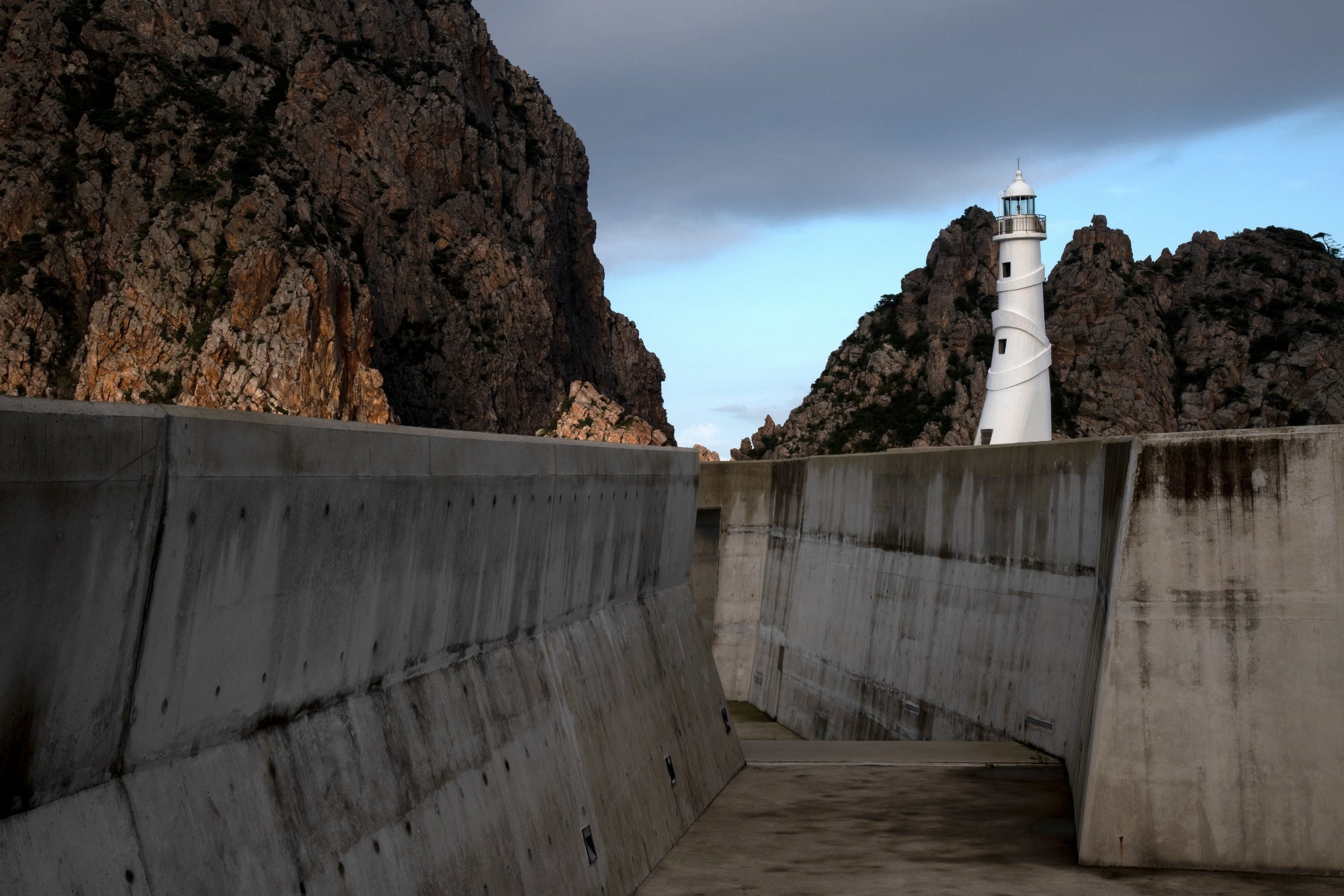 seawall with beach underneath and cliffs and lighthouse